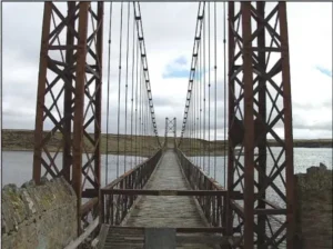 Acceso peatonal clausurado y pasarela de madera del puente colgante Bodie Creek Bridge en Malvinas.